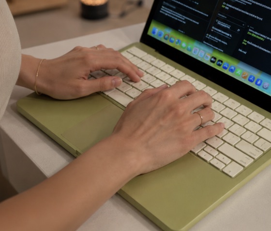 Hands typing on a MacBook, the Tansei shelf docked at the screen edge