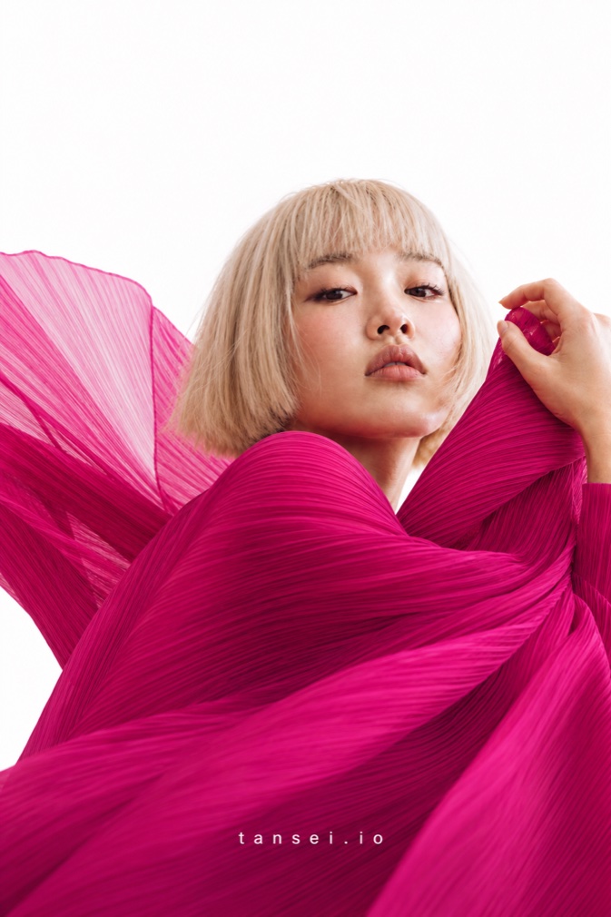 Tansei campaign photograph: model with pink pleated fabric sweeping across the frame